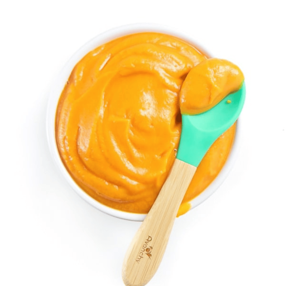 Small white baby bowl with a teal baby spoon on my kitchen white counter. The bowl is full of a smooth sweet potato puree.