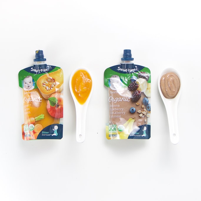 2 organic happy baby baby food pouches with spoons next the them with puree inside.