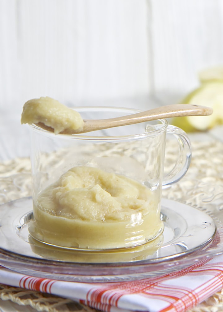 Glass bowl filled with homemade puree with spoon resting on top.