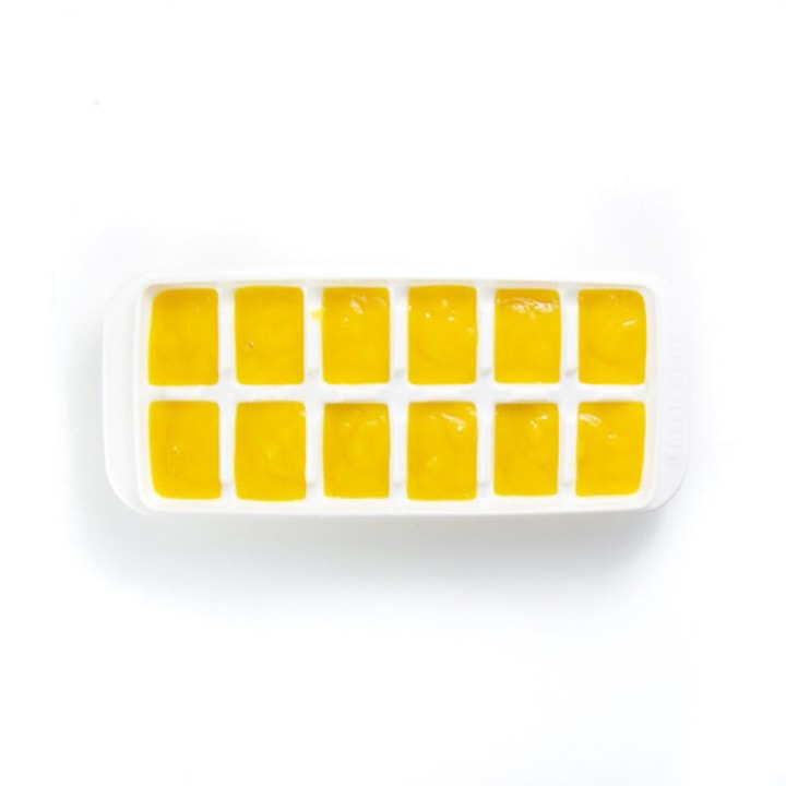 white ice cube tray full of yellow mango puree. 