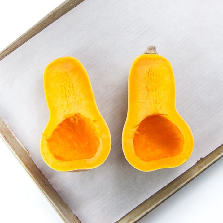 2 halves of a butternut squash resting on a baking sheet.