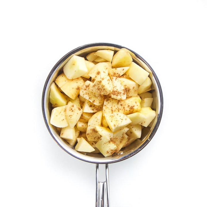 Apples in a saucepan with cinnamon sprinkled on top,