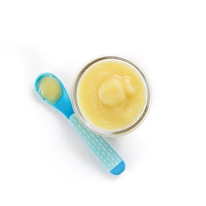 Small glass jar with spoon resting next to it.
