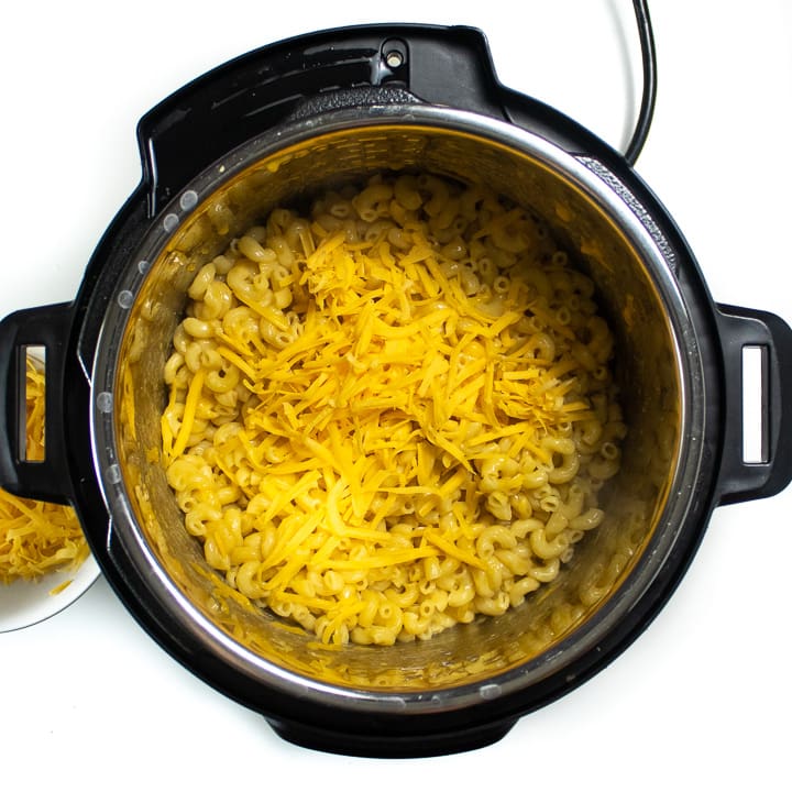Instant pot with cooked noodles and shredded cheese.