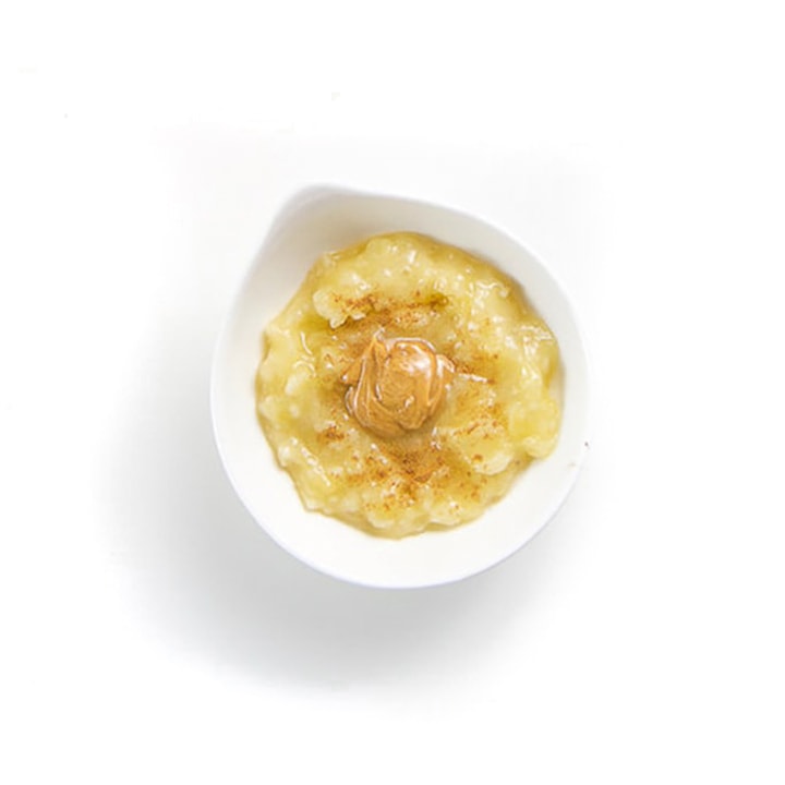 Small white bowl with banana puree and peanut butter inside.